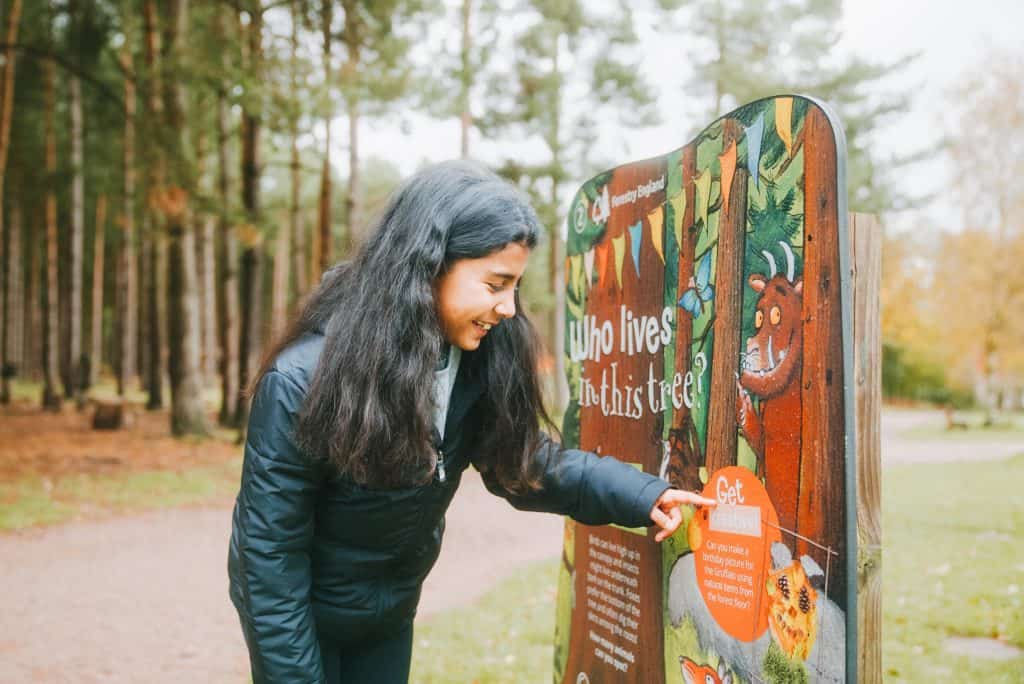 Girl looks at information board in forest