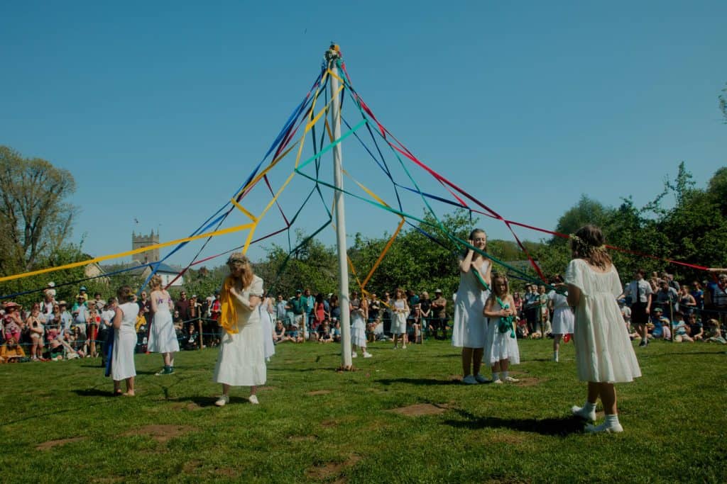 Children dance around a traditional may pole weaving colourful ribbons around the pole as their dance