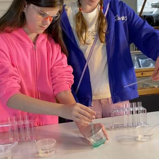 A young girls pours chemical while doing a science experiment