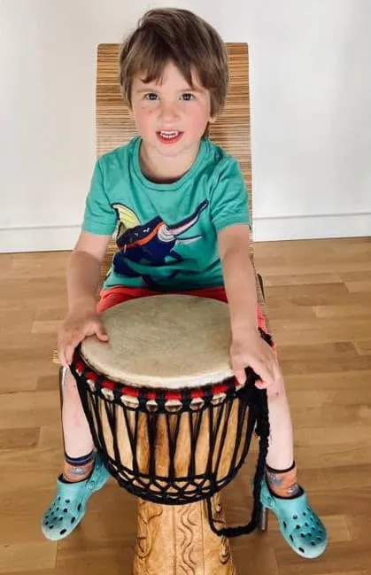 A boy sits in front of a tall drum