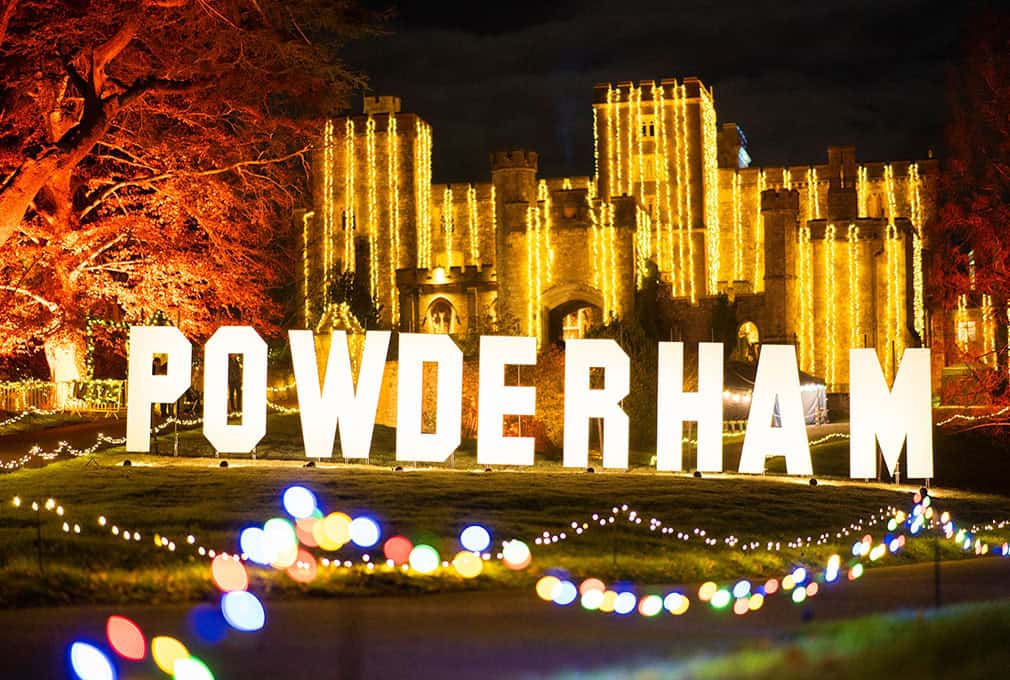 Illuminated Powderham sign in front of Powderham Castle at night