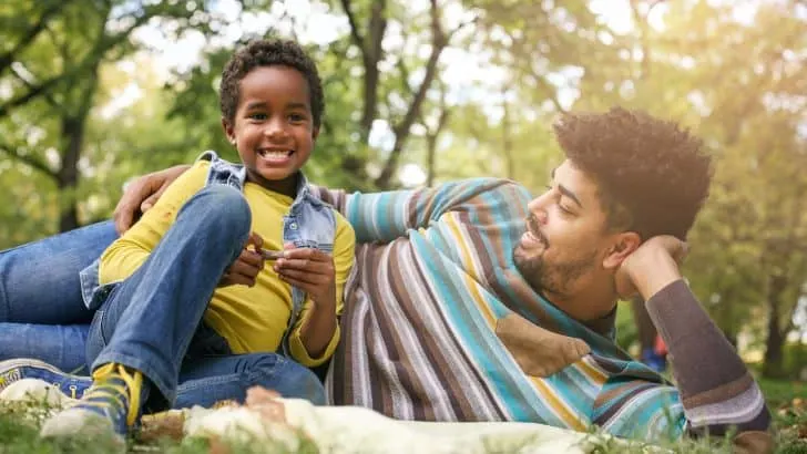 Father and daughter laying down in the park having a funny conversation