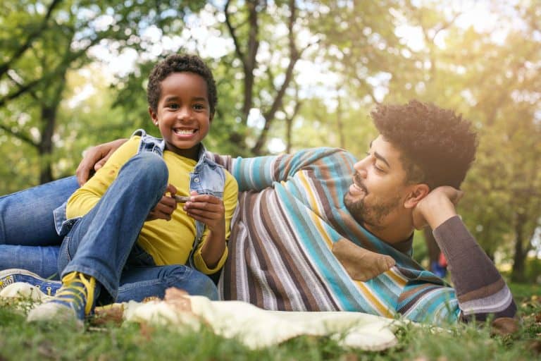 Father and daughter laying down in the park having a funny conversation