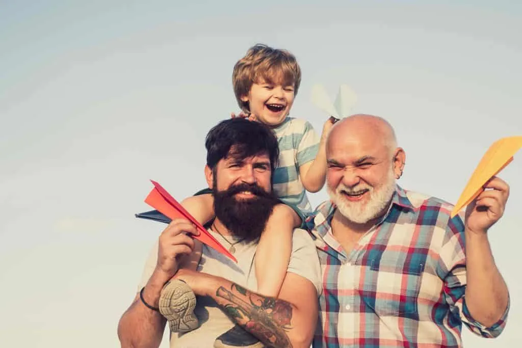 Three generations of a family play with paper planes. Father, Son and Grandson concept