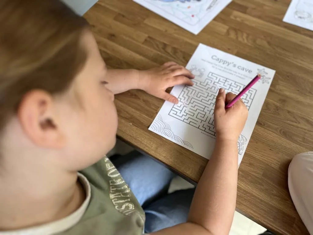 Close up of a child completing a maze activity sheet