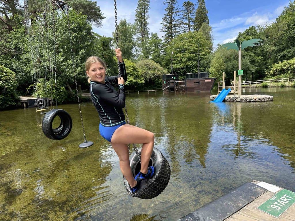 Eleven year old swinging on a tyre over the lake at River Dart Country Park