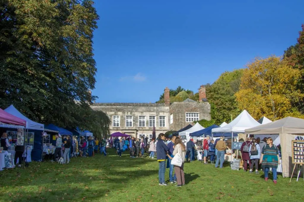 Market stalls lined up on the lawn outside Cockington Court on a sunny autumn day