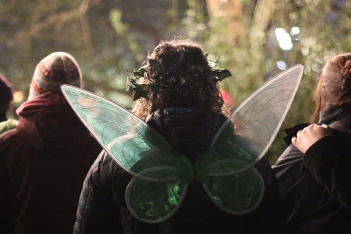 A visitor wearing fairy wings while at a Wassail event