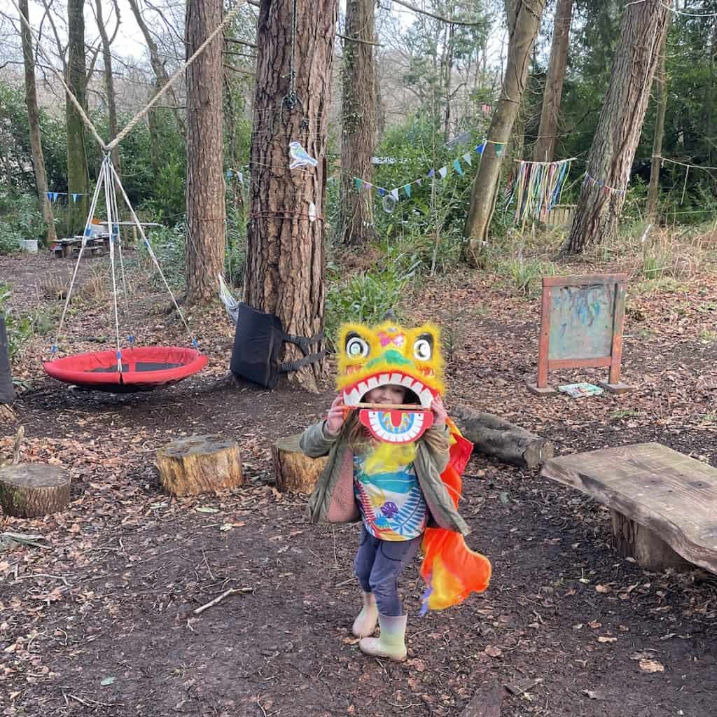 Child in woods wearing Chinese dragon mask