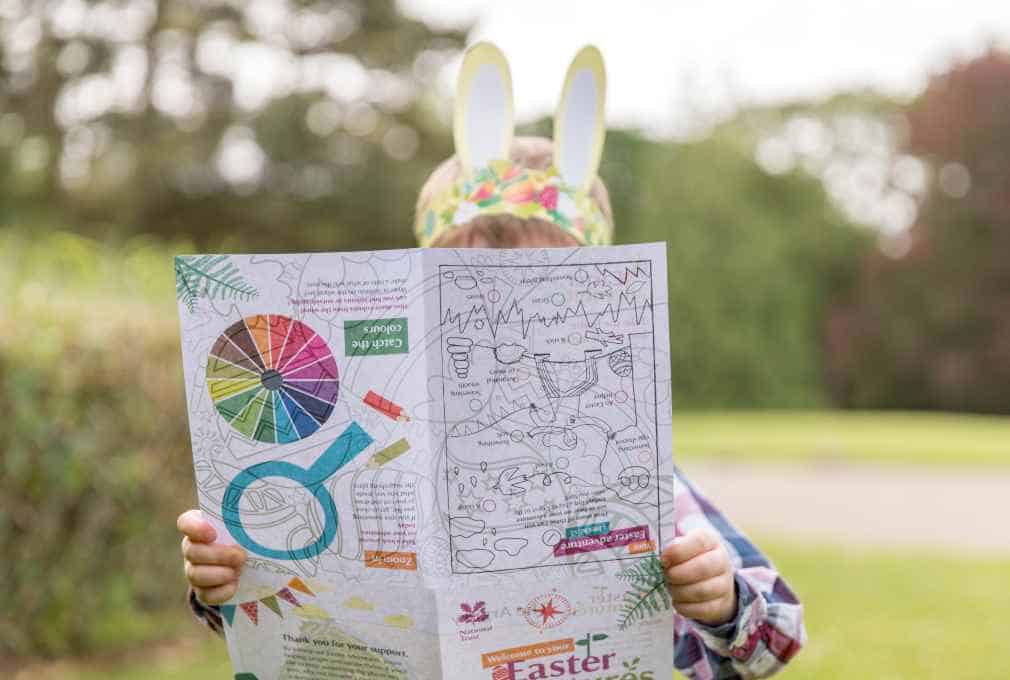 A child wearing paper bunny ears looks at at National Trust Easter trail sheet