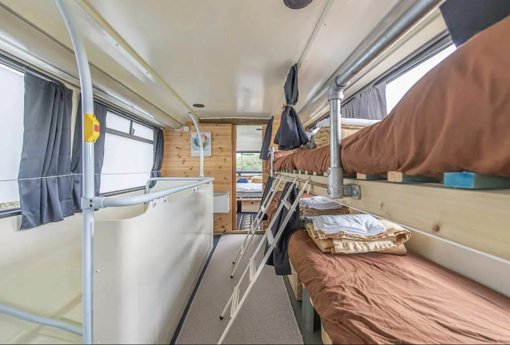 A bunk and single bed on the top deck of the double decker bus glamping accommodation at Dartmoor Reach farm