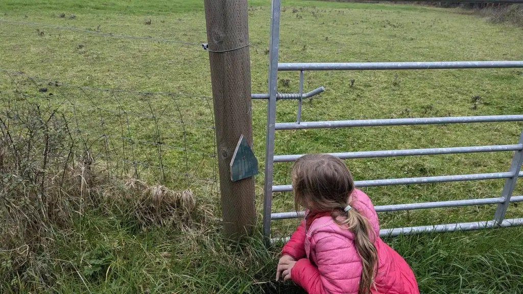 Stacey's daughter crouched by a gate looking at a fairy door