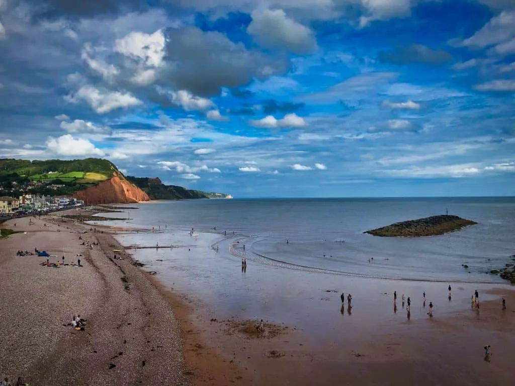 A view of Sidmouth Beach with the tide out and red cliffs in the background