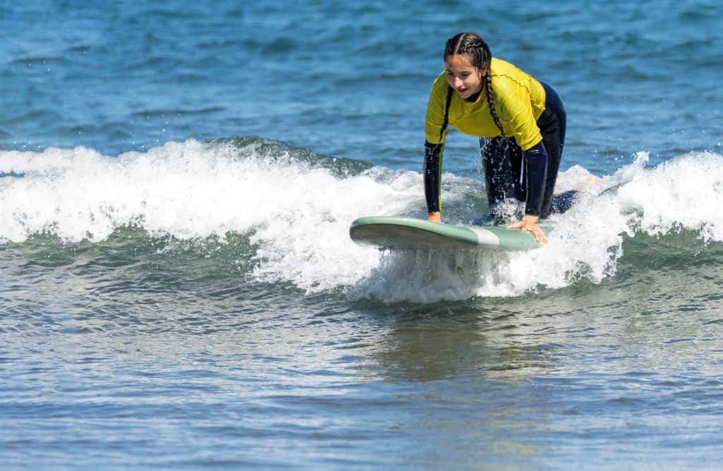 Young woman surfing while kneeling on a surfboard