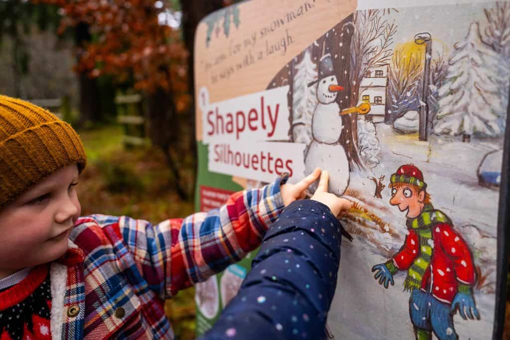 Children pointing to a activity board on the Stick Man Christmas trail