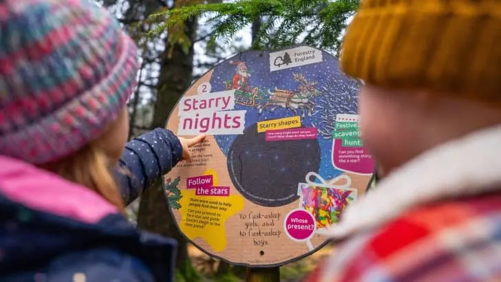 Children point to a Stick Man trail activity board