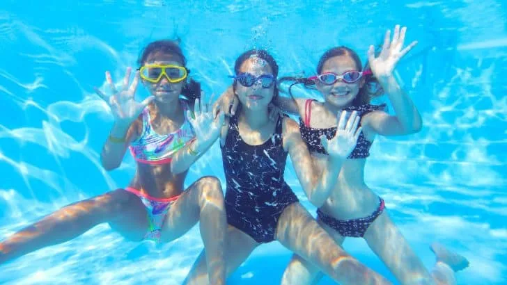 Happy girls waving under water in a swimming pool