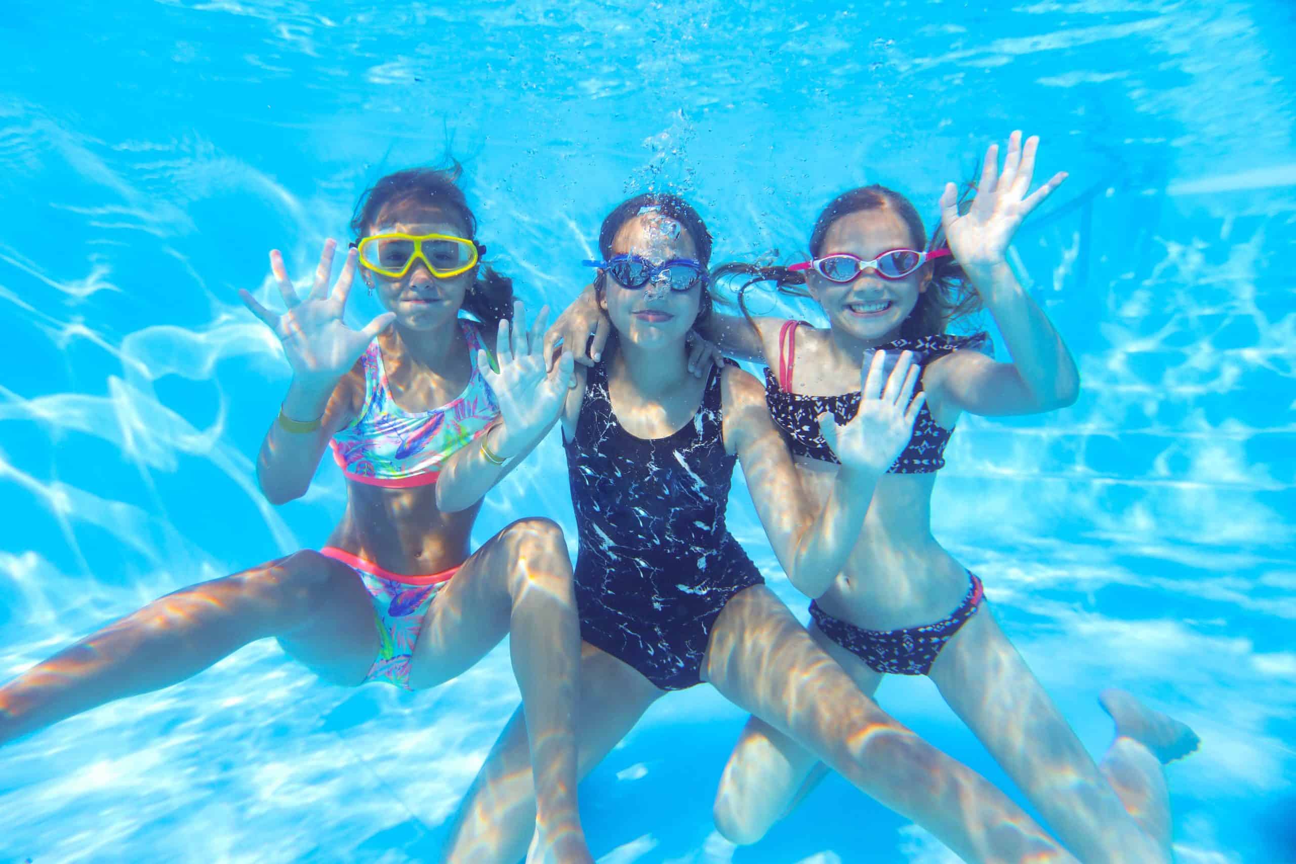 Happy girls waving under water in a swimming pool