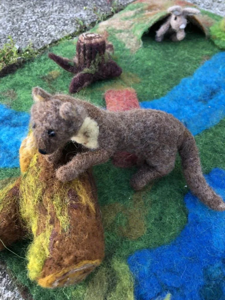 A weasel made of felt in a woodlands scene