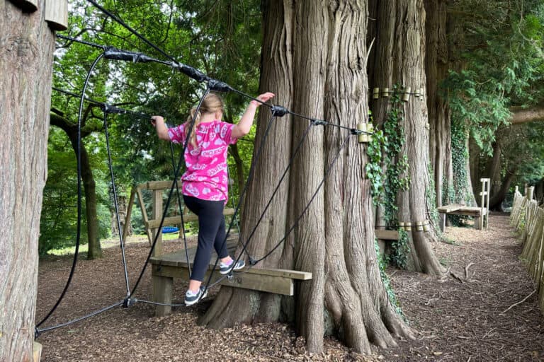 Girl walking along a rope bridge in the assault course at River Dart Country Park