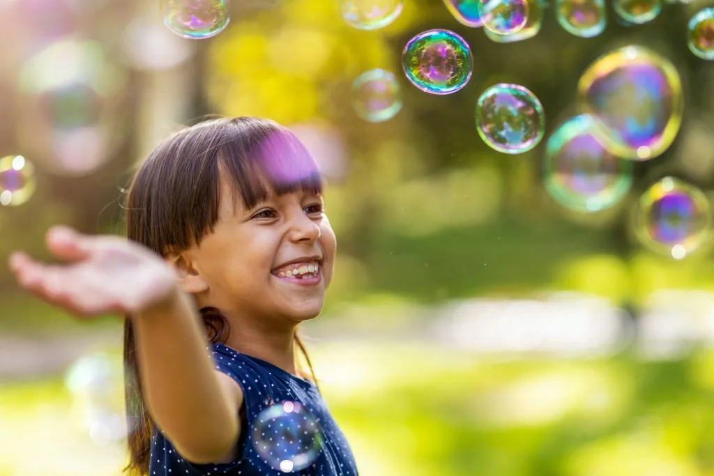 Girl chasing bubbles outdoors