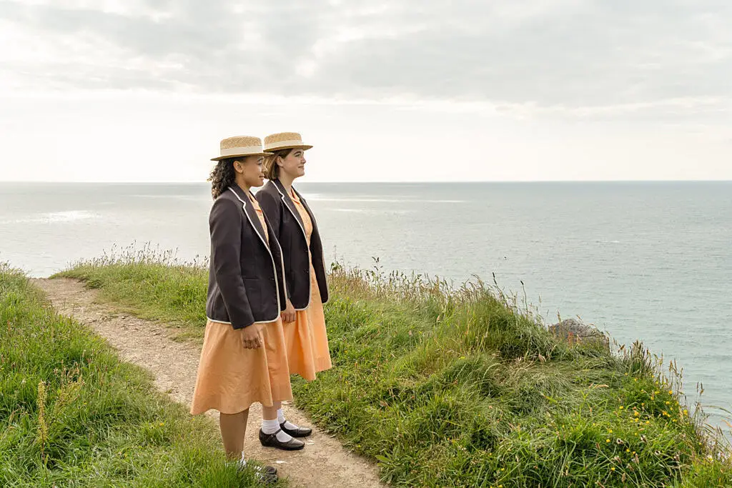 Malory Towers pupils stand on a cliff overlooking the sea