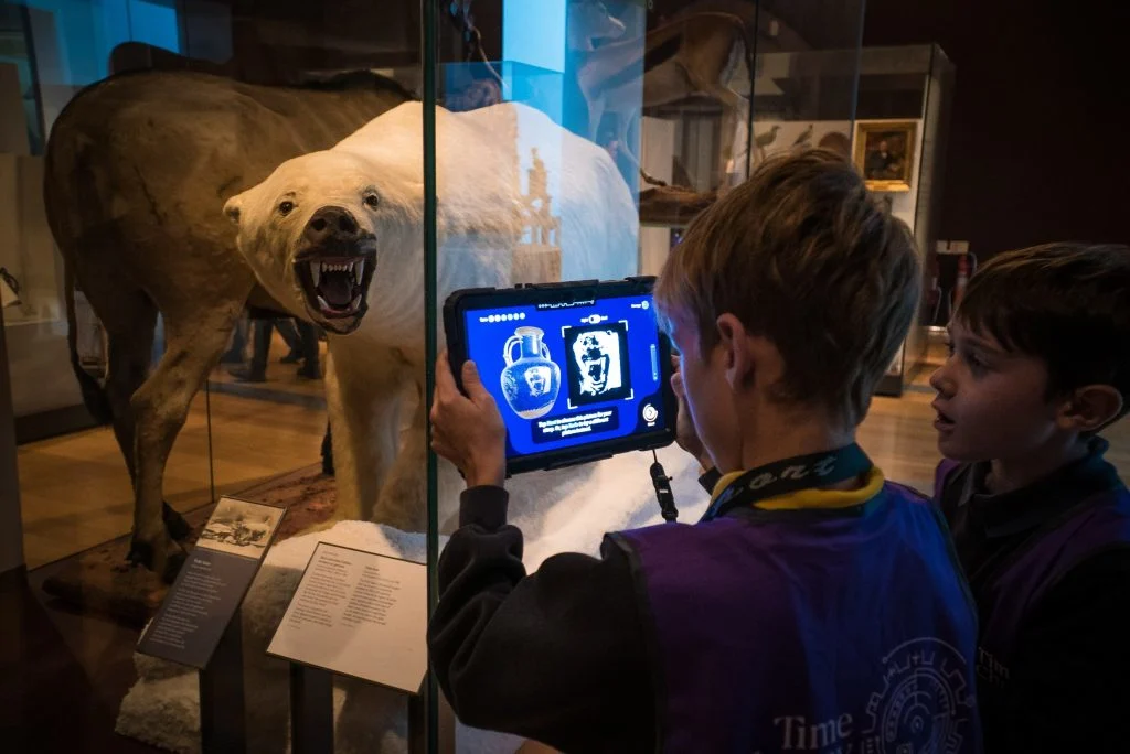 Children look at the polar bear exhibit nat RAMM in Exeter using a tablet device