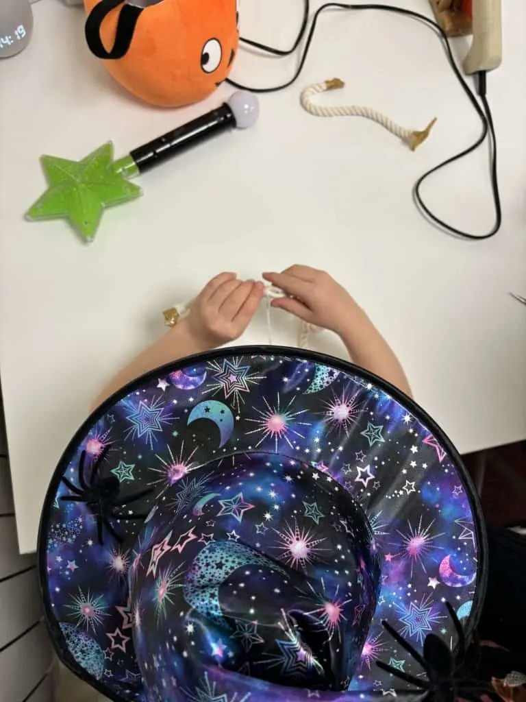Child wearing a witches hat sat a a table crafting