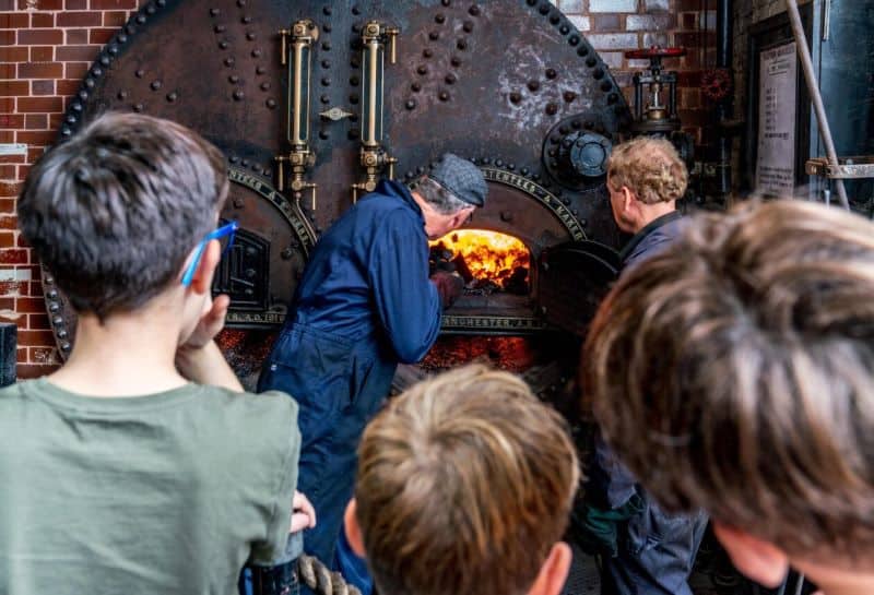 Visitors gather round to watch a steam engine being stopped up with fuel