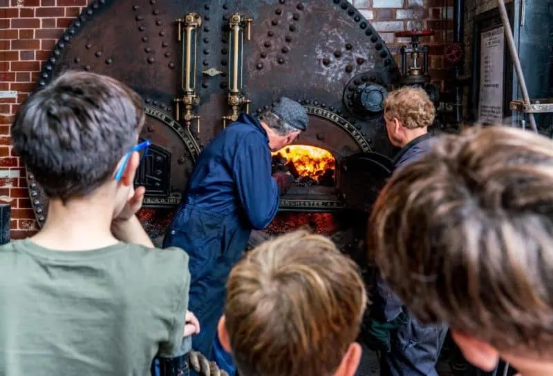 Visitors gather round to watch a steam engine being stopped up with fuel