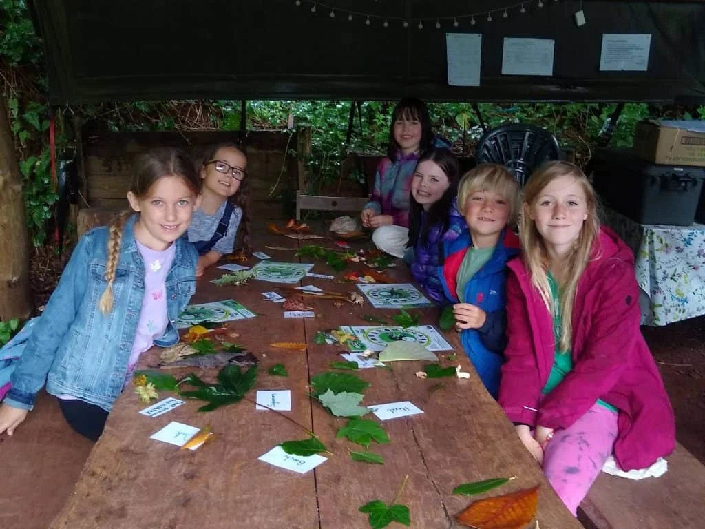 Children sit around a table in a woodland classroom