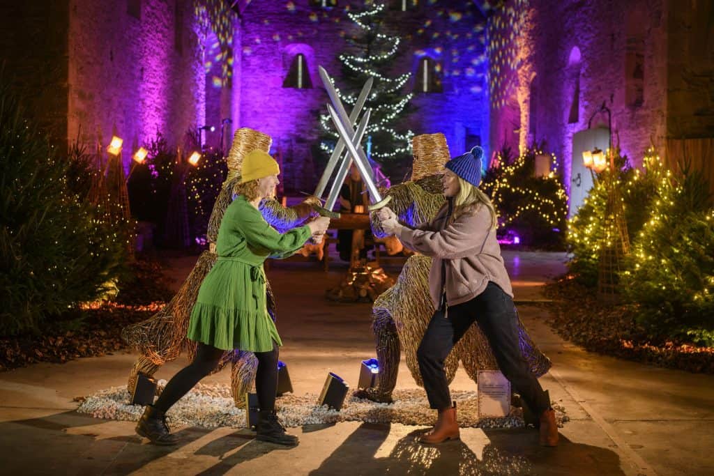 Buckland Abbey brings the legends of King Arthur to life this Christmas
Buckland Abbey near Plymouth will open its doors on Saturday 29 November for a Christmas season inspired by the legendary tales of King Arthur. Running until 4 January, this year’s display transforms the medieval Great Barn and the Abbey into a world of myth, magic and winter storytelling.
Visitors stepping into the Great Barn will find themselves in a shimmering forest of Christmas trees, accompanied by the atmospheric sounds of animals and an icy winter breeze. Here, the story of Gawain and the Green Knight begins, before guests move into King Arthur’s court where a dramatic willow sculpture of Gawain’s battle -lit in green and gold - creates a striking centrepiece. Clashing swords and a crackling fire soundtrack the scene as Arthur looks on. (Volunteers & House Staff pictured)
