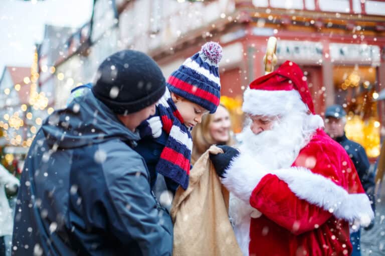 Little toddler boy with father on Christmas market. Funny happy kid taking gift from bag of Santa Claus. holidays, christmas, childhood and people concept