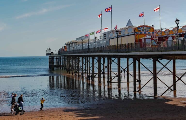 Pier at the English Rivera. A colourful picture of families on holiday and enjoying the winter sunshine at the seaside. Reflective water on a bright day.