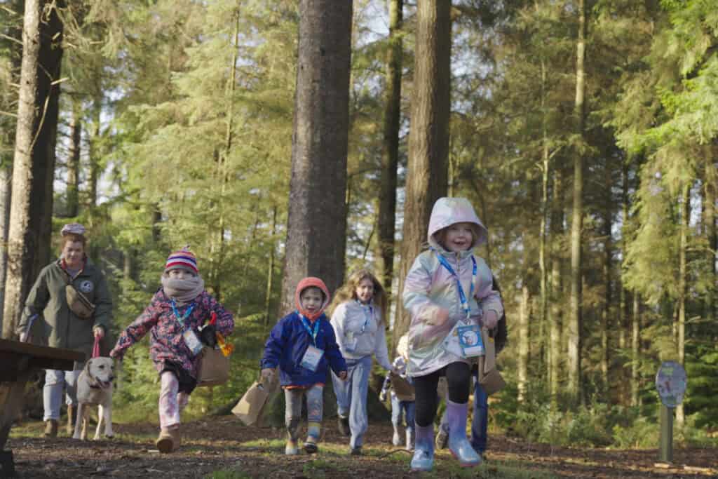 Running children wrapped up in winter clothes for a woodland walk.