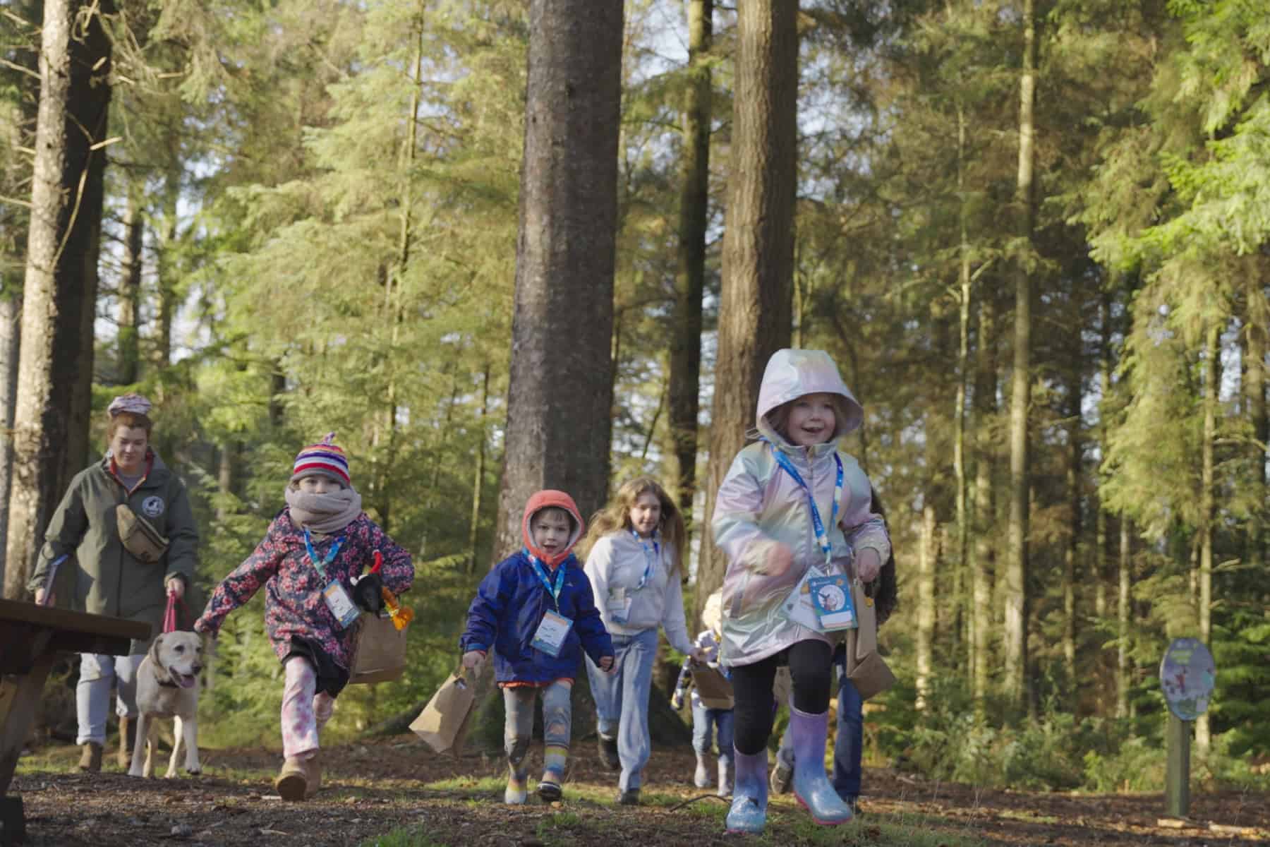 Running children wrapped up in winter clothes for a woodland walk.