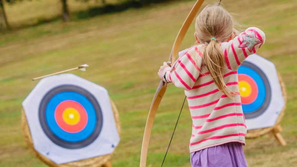 Child aiming an arrow at an archery target
