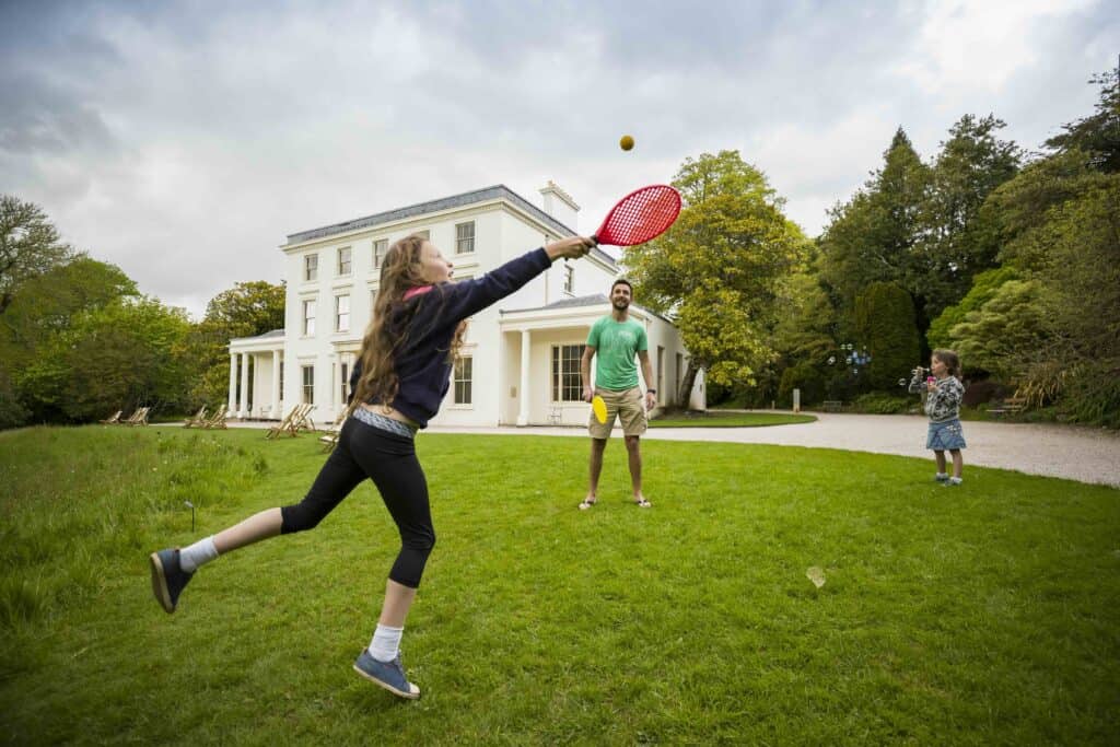A family playing bat and ball in the garden at Greenway, Devon