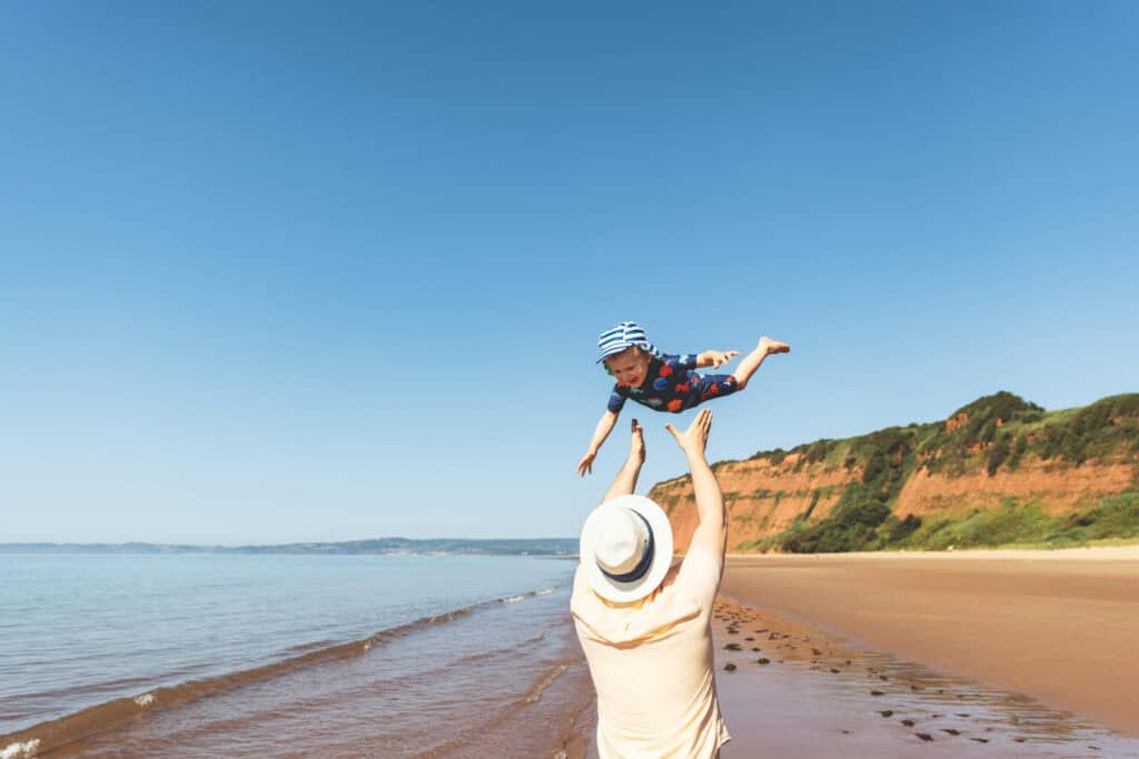 Father and child on Sandy Bay Beach at Devon Cliffs Holiday Park