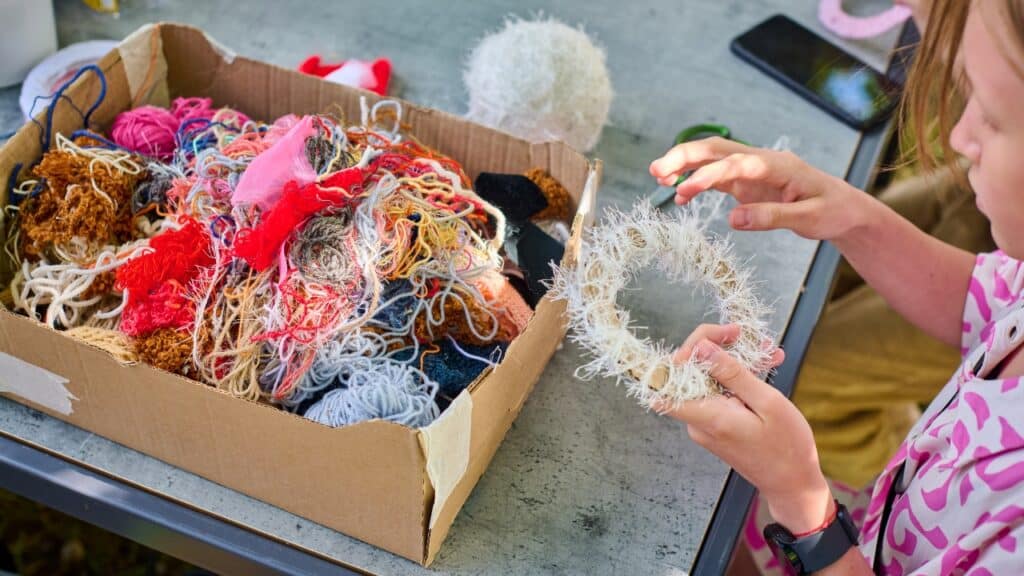 Child using colourful wool to weave around a circle shape