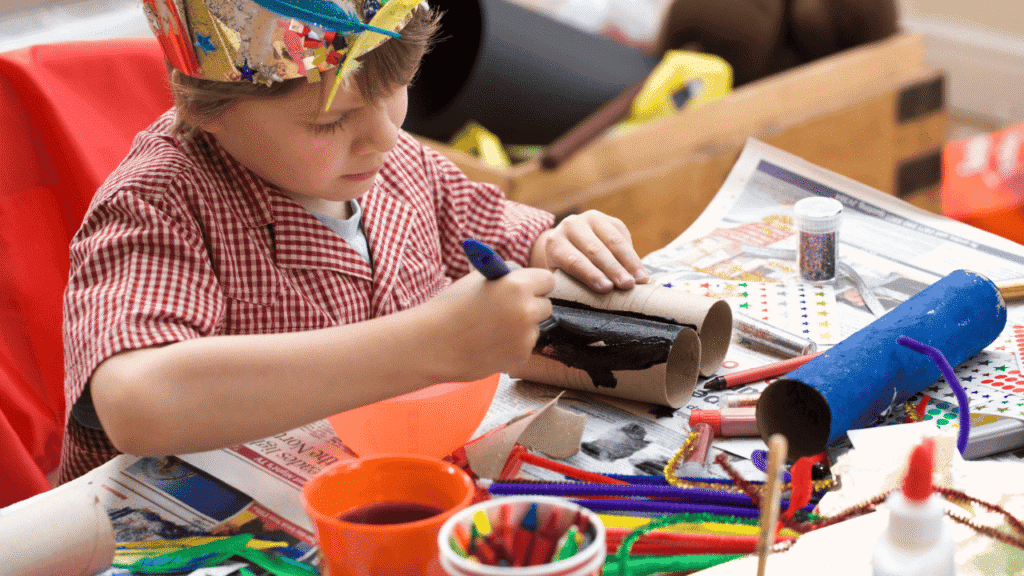 Boy crafting a rain stick from cardboard tubes and decorating it