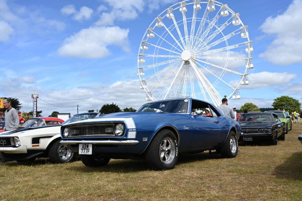 Classic American car at the Cofton Car Show with a big wheel in the background