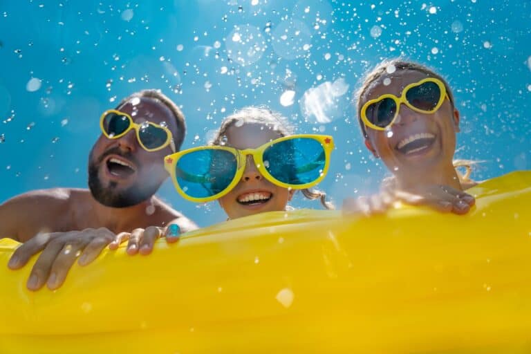 Family having fun on summer vacation. People jumping in swimming pool. Active lifestyle concept
