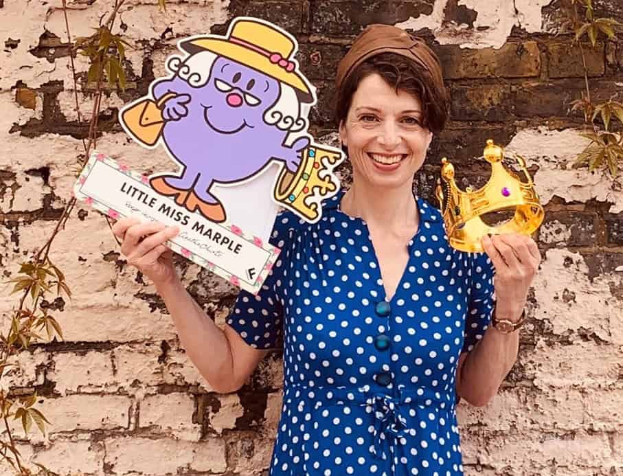 Storyteller holding Little Miss Marple book and crown